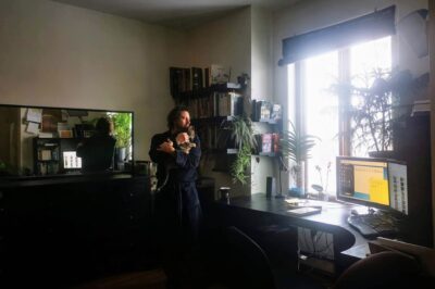Carl Boileau dans son bureau à Montréal tenant sa chatte Jade près de la fenêtre entourée de plantes.